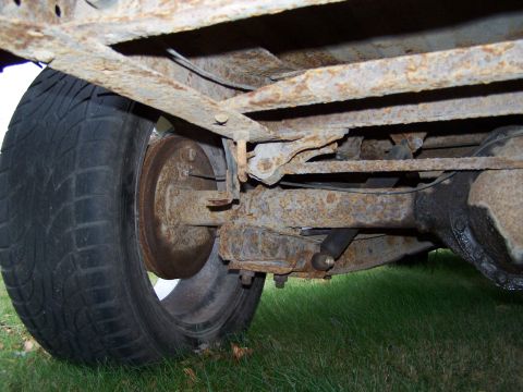 1969 Chevrolet C/K Pickup - The rear suspension and wheel assembly of a heavily rusted truck are shown from the side.