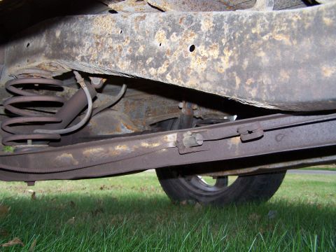 1969 Chevrolet C/K Pickup - The heavily rusted frame and suspension components of a vehicle are shown from underneath.