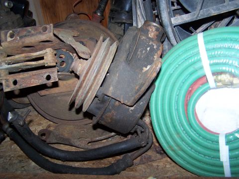 1969 Chevrolet C/K Pickup - Various automotive parts, including a power steering pump and pulley, are piled together with a green garden hose.