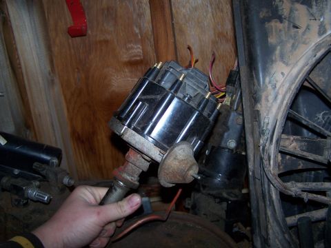 1969 Chevrolet C/K Pickup - A close-up view of a car's distributor assembly, held by a person's hand.