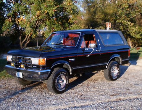 1989 Ford Bronco - This black 1989 Ford Bronco features a red interior and is shown in a three-quarter front view.