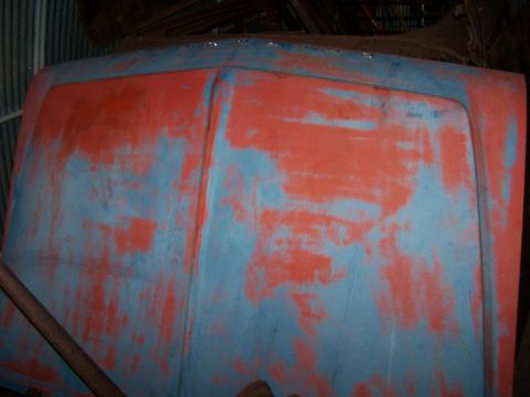 1969 Chevrolet C/K Pickup - Close-up of a truck hood showing layers of peeling red and blue paint.
