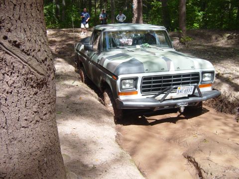 1979 Ford Bronco - This Ford pickup truck, painted in camouflage, is driving through a muddy off-road course.