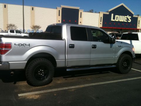 1995 Ford Bronco - Silver Ford F-150 parked in front of a Lowe's store. The truck has a 4x4 Off Road decal on the fender.