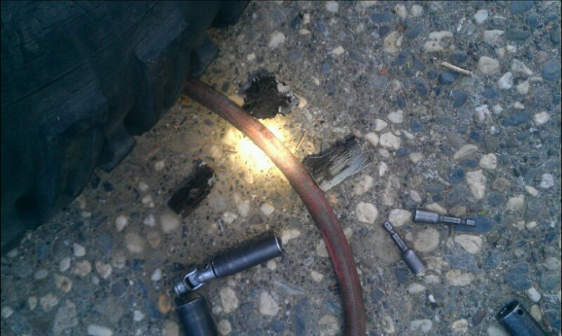Tire tread and socket wrenches on asphalt with a red hose