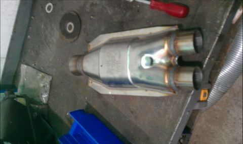 1986 Ford Bronco - A catalytic converter is shown on a workbench, with part numbers visible on its casing.