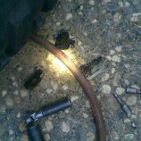 1986 Ford Bronco - Tools and a tire are visible on a gravel surface, suggesting a repair or maintenance activity.