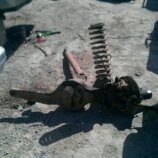 1986 Ford Bronco - A disassembled front axle assembly, including a coil spring and shock absorber, lies on the ground.