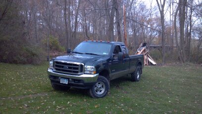 1993 Ford F-150 - A dark green Ford F-250 Super Duty pickup truck is parked in a yard with a pile of firewood in the background.