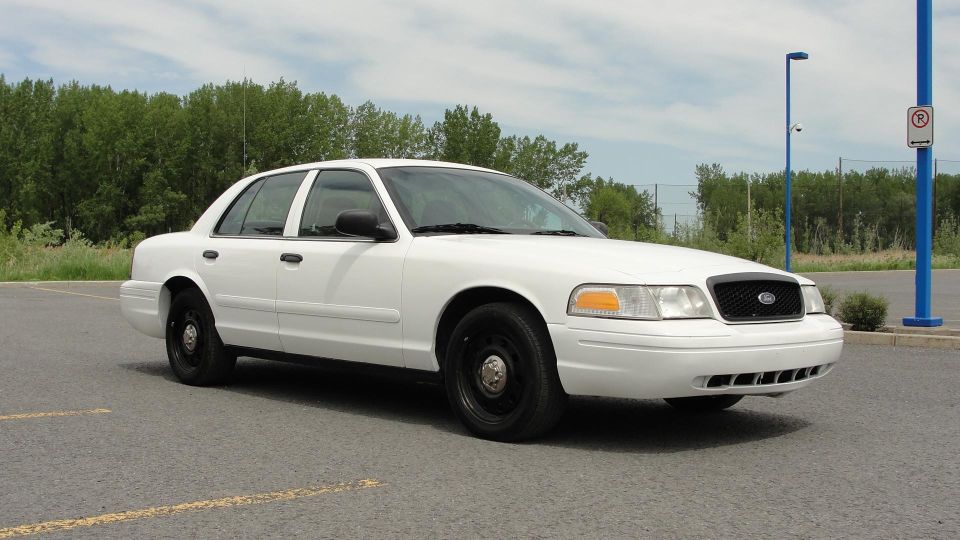 White 2006 Ford Crown Victoria parked on asphalt, front 3/4 view, black steel wheels, clear sky