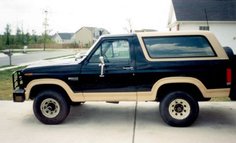 1983 Ford Bronco - Side profile of a 1983 Ford Bronco with a two-tone black and tan paint scheme.