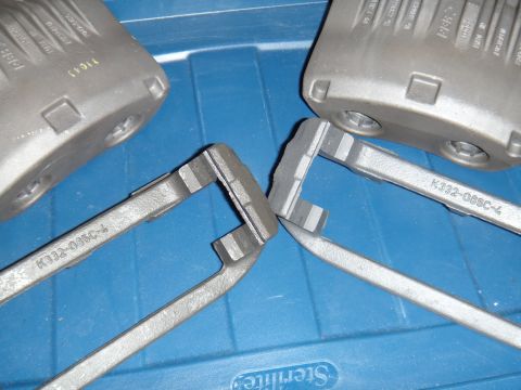 2003 Ford Taurus - Close-up of brake caliper parts, some with visible part numbers, resting on a blue container.