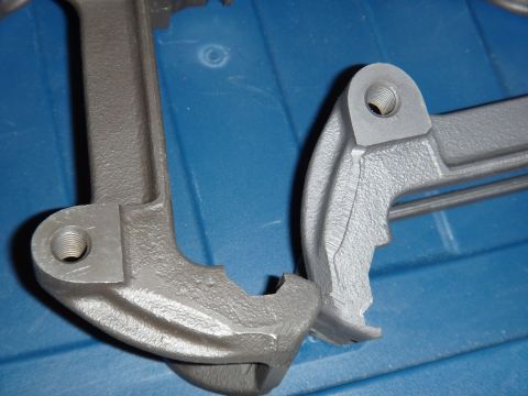 2003 Ford Taurus - Two gray metal brake caliper parts are shown on a blue surface. The registry claims they are from a 2003 Ford Taurus, but this cannot be ve…