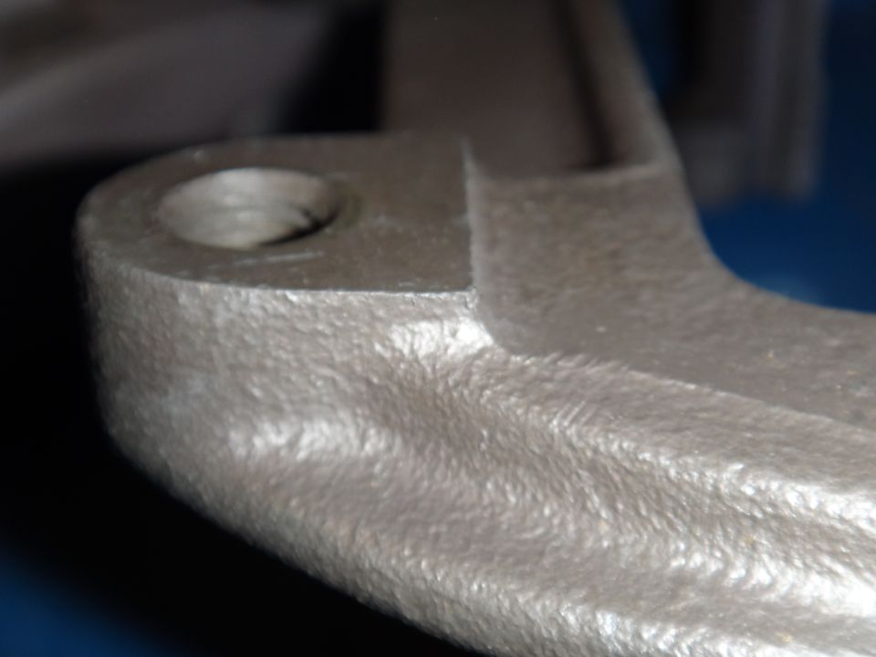 Close-up of a cast metal bracket with a hole for a bolt
