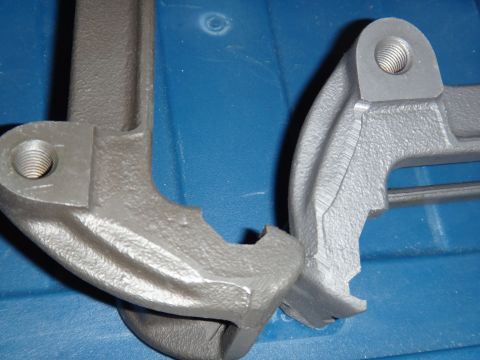 2003 Ford Taurus - Two gray metal brake caliper brackets are shown, one in sharper focus than the other.