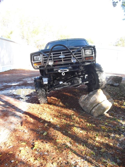 1986 Ford Bronco - This heavily modified black SUV, likely from the early 1980s, is shown navigating rocky terrain.