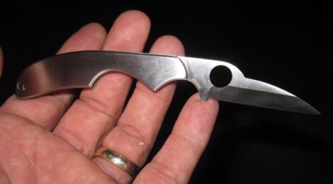 1990 Ford Bronco - A silver folding knife with a unique bird-head blade shape is displayed in a hand, with 'CHINA' marked on its surface.