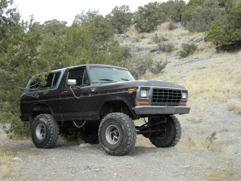1979 Ford Bronco - This lifted Ford Bronco sits on a dirt road with dry brush and hills in the background.