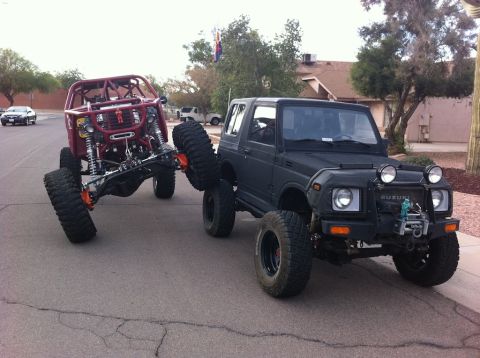 Suzuki Samurai - A Suzuki Samurai tows a heavily modified off-road buggy, extreme suspension and large tires.
