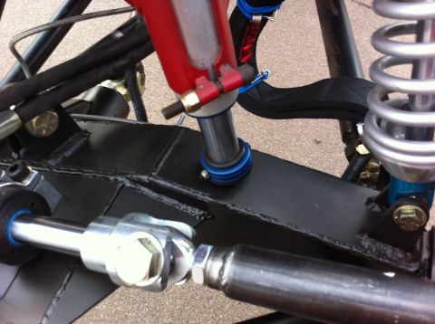 Suzuki Samurai - Close-up view of a custom front axle assembly, red and blue suspension components and a SuperMotors.net watermark.