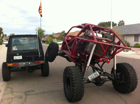 Suzuki Samurai - Suzuki Samurai and a custom buggy with extreme off-road modifications are parked on a street.