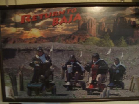 1988 Ford Bronco - A group of people on mobility scooters are posed in a desert scene with a "Return to Baja" graphic above.