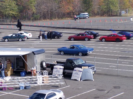 1999 Ford Crown Victoria - Multiple vehicles are parked on a paved surface, possibly a race track, with a trailer and a pickup truck in the foreground.
