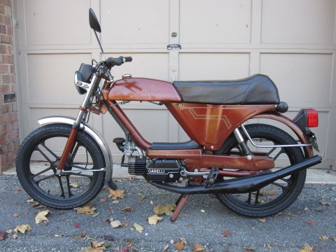 1981 Garelli Rally Sport - A brown moped is shown from the side, parked in front of a garage door.