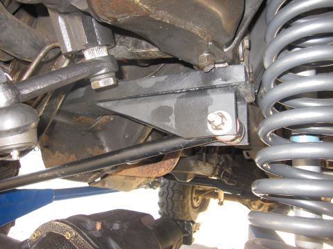 1985 Ford Bronco - Close-up view of a vehicle's suspension system, showing springs, steering components, and a tire. The Supermotors logo is visible in the lo…
