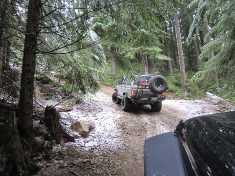 2008 Jeep Wrangler - A silver Jeep Cherokee XJ navigates a snowy forest trail, with another vehicle visible in the foreground.