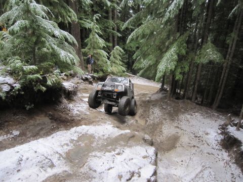 2008 Jeep Wrangler - An off-road vehicle tackles a challenging, snow-dusted trail through a dense forest.
