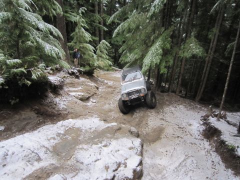 2008 Jeep Wrangler - Off-road vehicle tackles a challenging trail with snow and mud in a wooded area.