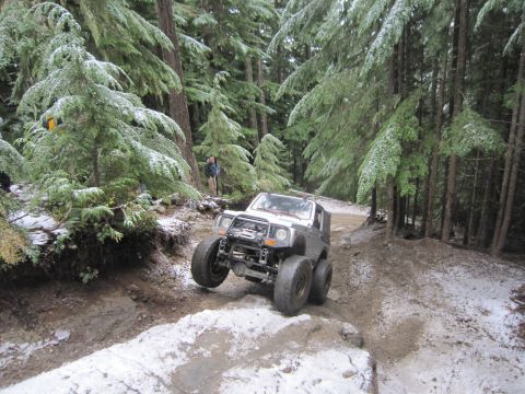 2008 Jeep Wrangler - A modified off-road vehicle tackles a challenging path in a snow-dusted forest.