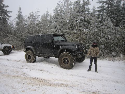 2008 Jeep Wrangler - A black Jeep Wrangler is parked in a snowy landscape with a person standing beside it.
