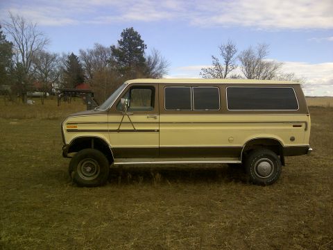 1979 Ford E250 - This lifted van is parked in a field under a cloudy sky.