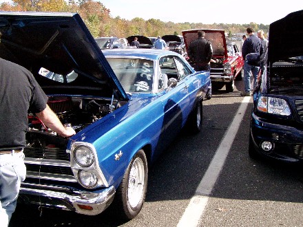 1999 Ford Crown Victoria - A blue 1966 Ford Fairlane 500 is displayed with its hood open at a car show.