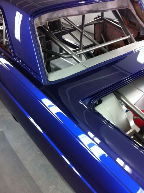 1965 Ford Fairlane - The interior of a custom blue vehicle shows a prominent roll cage structure.