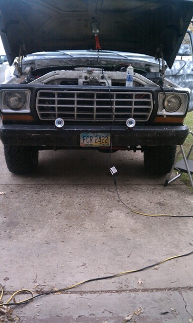1978 Ford Bronco - The front of a 1978 Ford Bronco is shown with its hood up, revealing the engine compartment and a license plate.