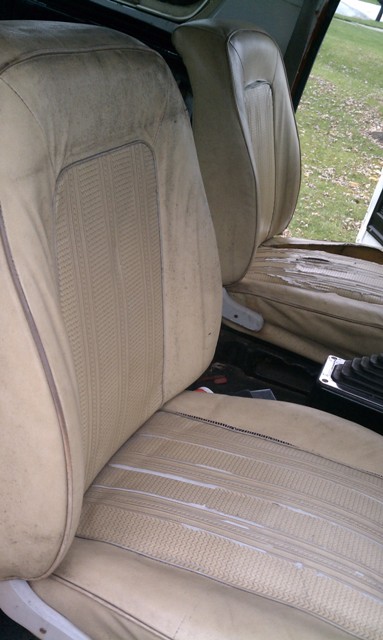 1978 Ford Bronco - Interior view of worn tan seats in a 1978 Ford Bronco, showing damage to the passenger seat upholstery.