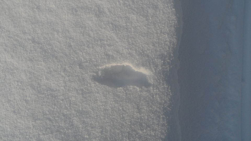 Shadow of a car shape on a snow-covered surface