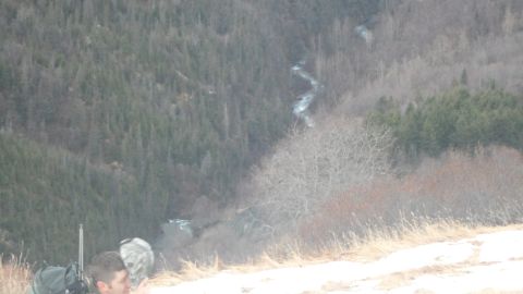 1986 Chevrolet Blazer - A person with a rifle surveys a vast, wooded landscape with a river flowing through the valley below.