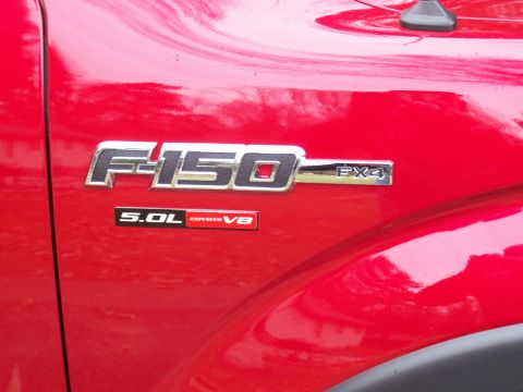 1978 Ford F-150 - Close-up of the F-150 FX4 5.0L Coyote V8 emblem on a red vehicle.