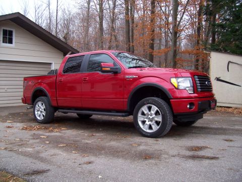1978 Ford F-150 - A red Ford F-150 pickup truck is parked in a driveway with a garage and trees in the background.
