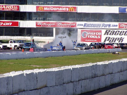 1999 Ford Crown Victoria - A drag racing event is underway with multiple vehicles and spectators in the grandstands.