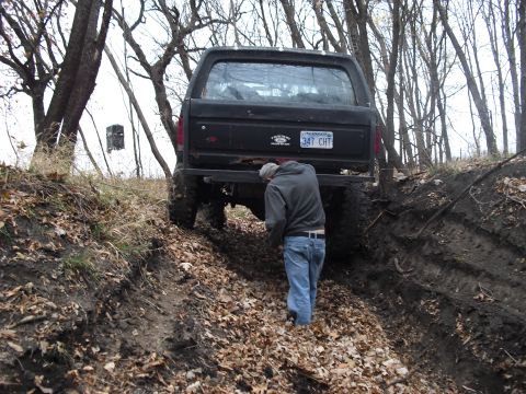 1986 Ford Bronco - A 1986 Ford Bronco navigates a challenging off-road trail in a wooded area.