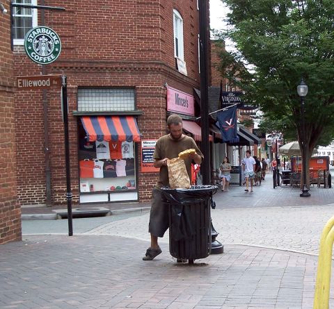 1971 Ford Ranchero - A man discards food into a public trash receptacle on a busy street corner.