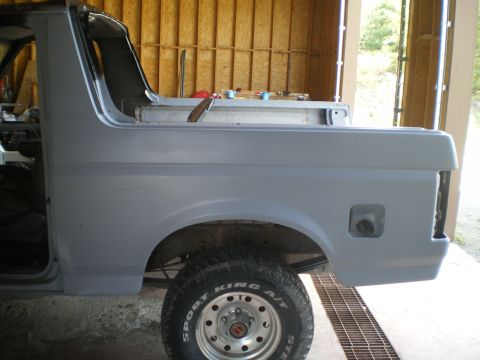 1988 Ford Bronco - This vehicle's body is undergoing preparation, with primer applied to the rear section and a visible tire.
