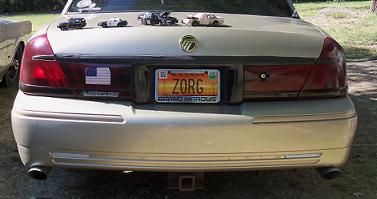 2000 Mercury Grand Marquis - The rear of a 2000 Mercury Grand Marquis is shown, with a hitch receiver and several toy cars displayed on the trunk lid.