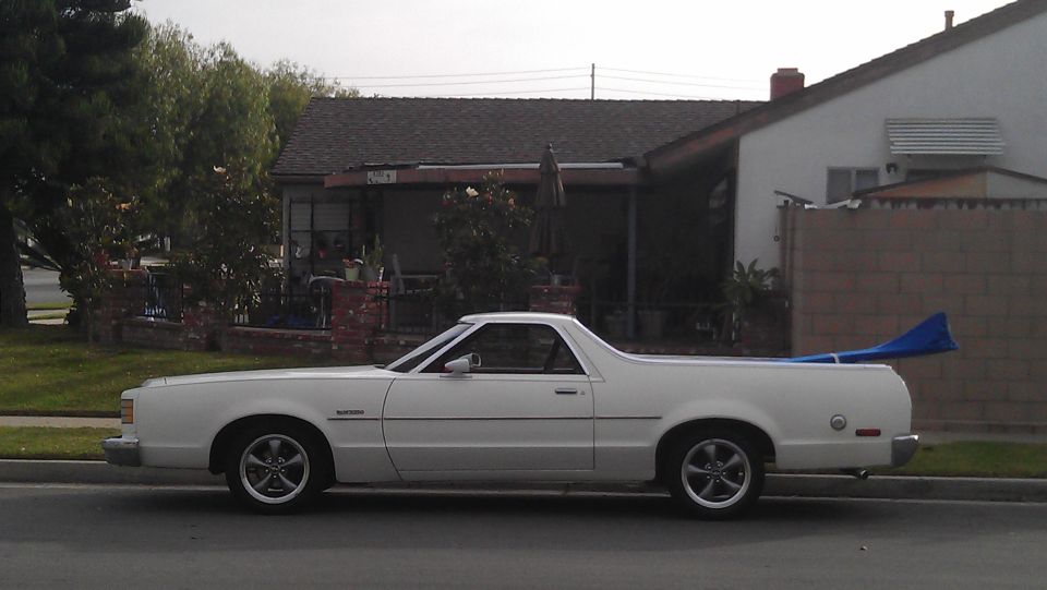 White Ford Ranchero pickup in side profile parked at a residential curb.
