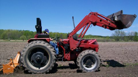 2000 Chevrolet Tahoe - Tractor with front loader in a field under a clear blue sky.